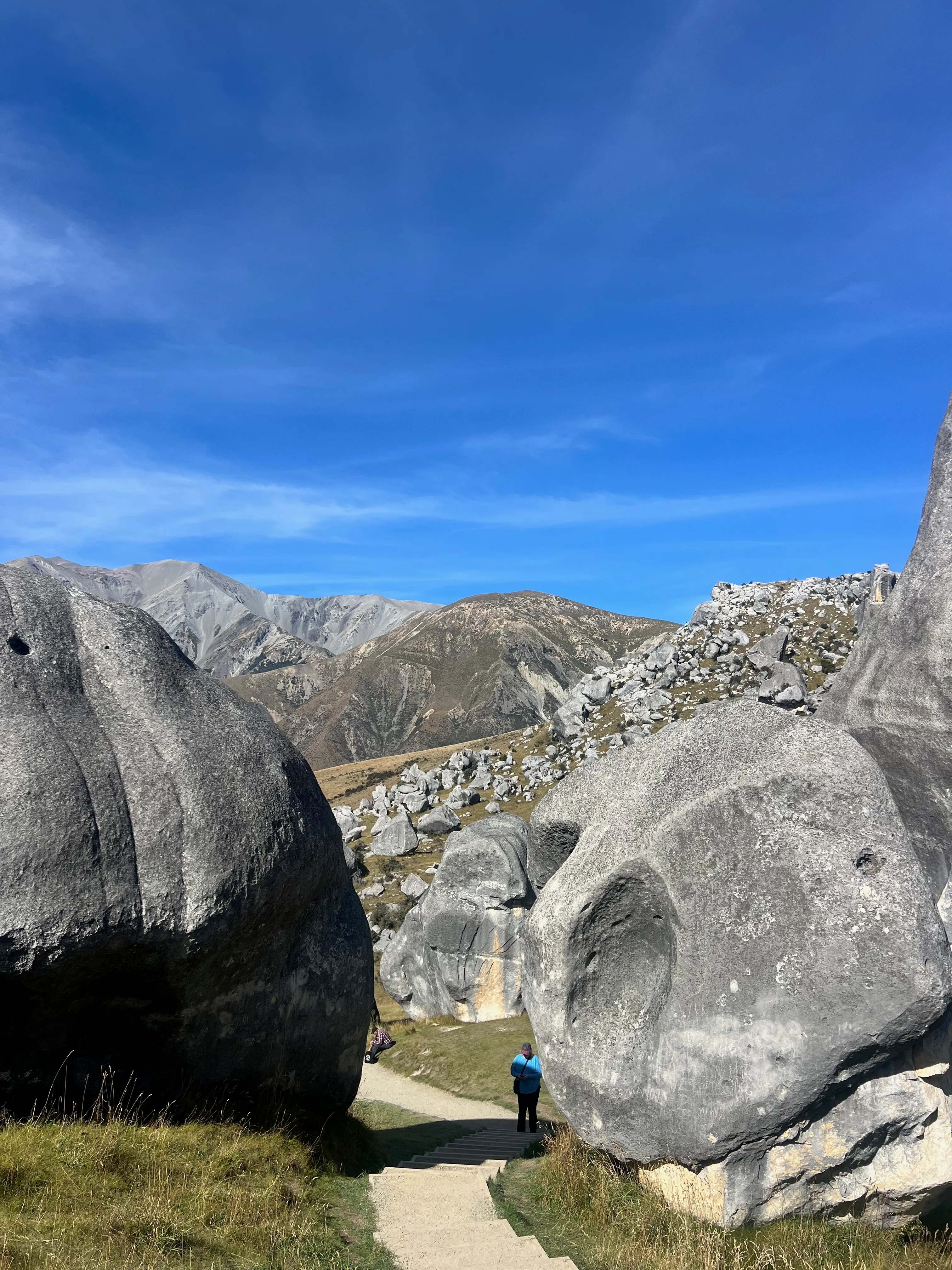 A walker between two huge rounded limestone boulders.