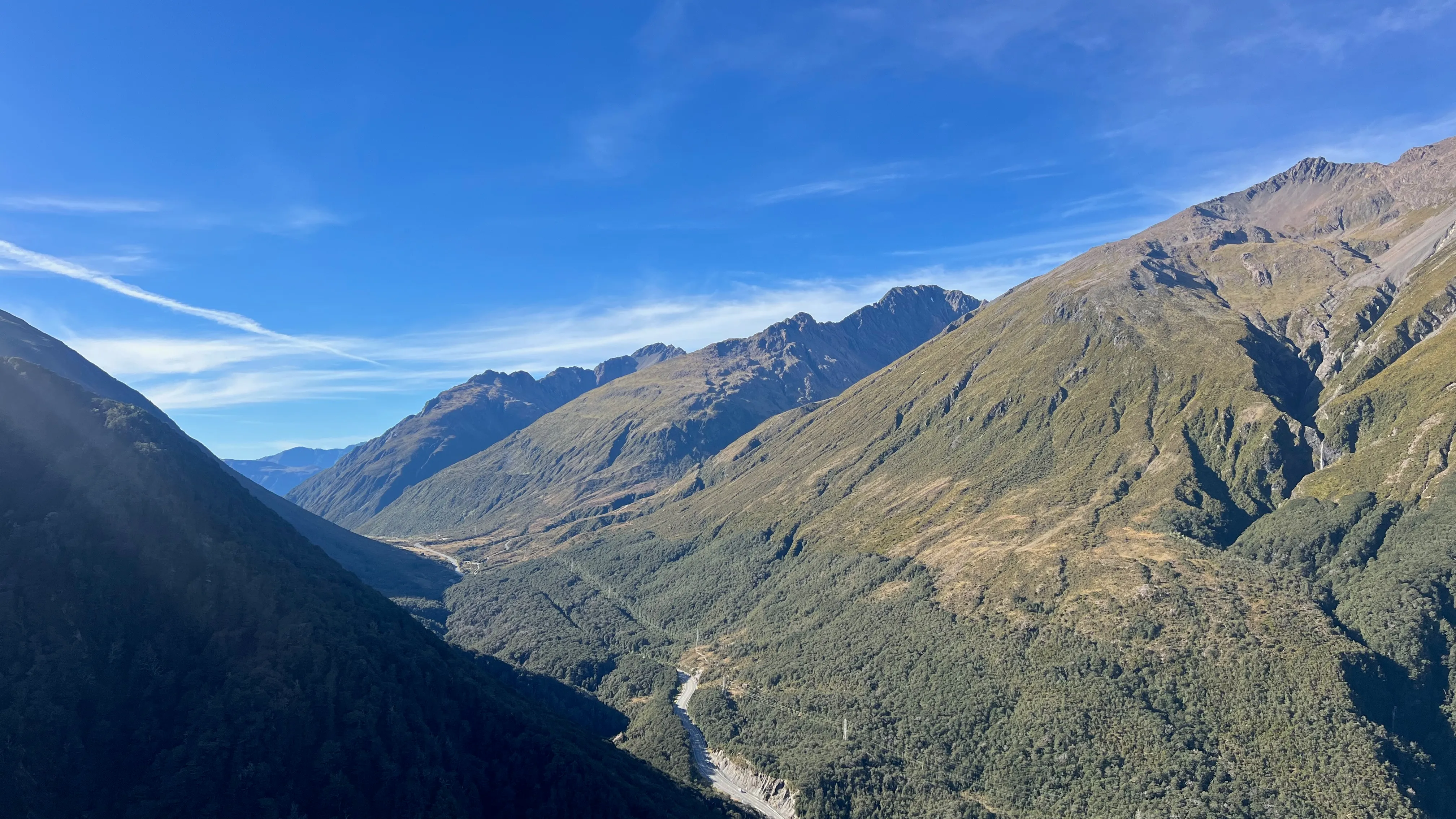 A braided river winding through a deep forested valley between mountains.