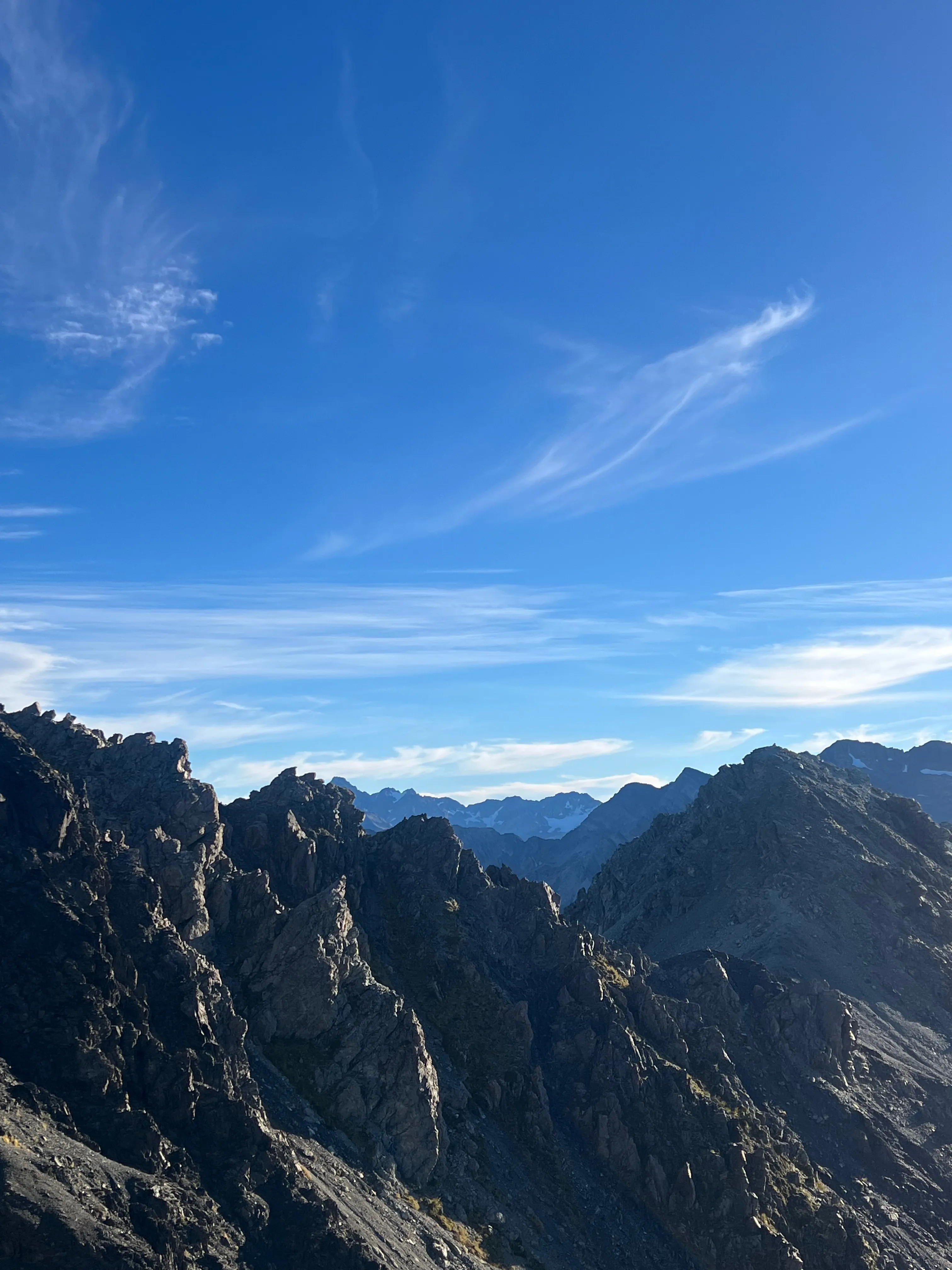 Jagged dark rock pinnacles below a sky of wispy clouds.