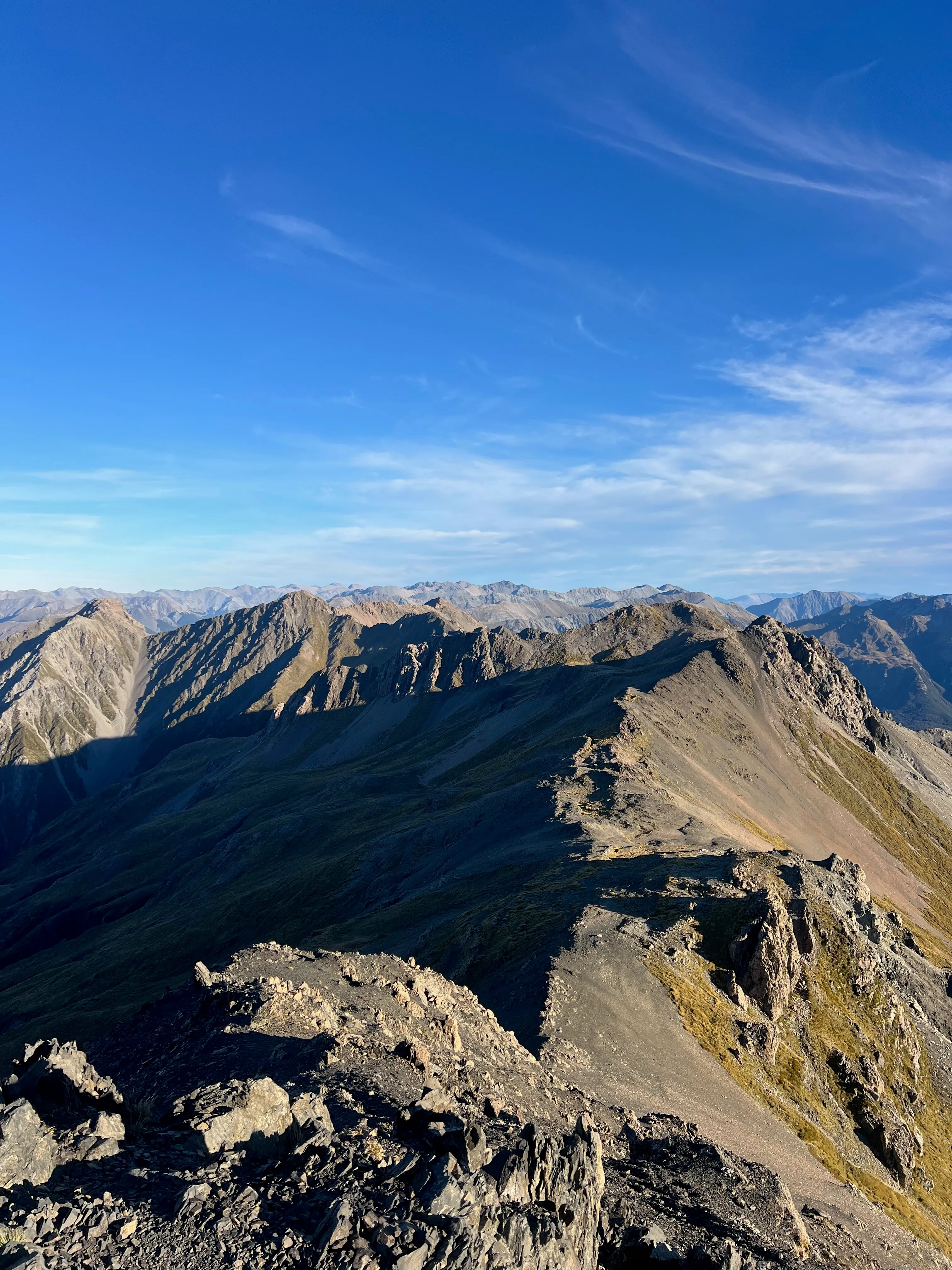 A sharp rocky ridge running away from the summit under a blue sky.