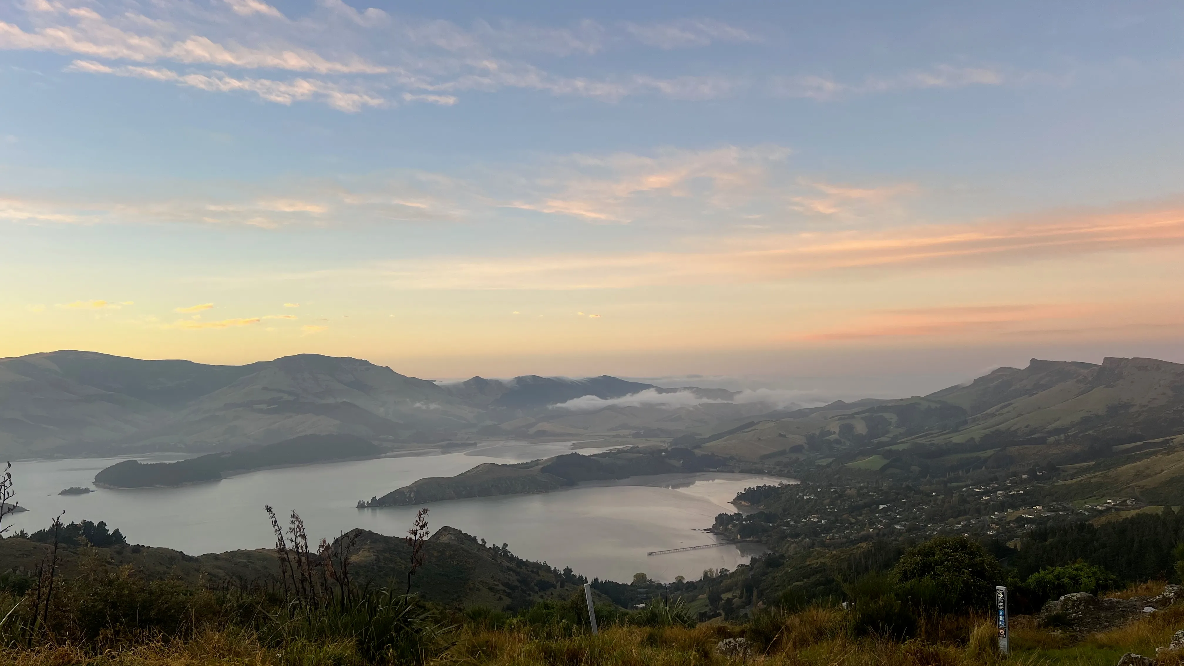 Lyttelton Harbour and its hills at sunrise, seen from high above.