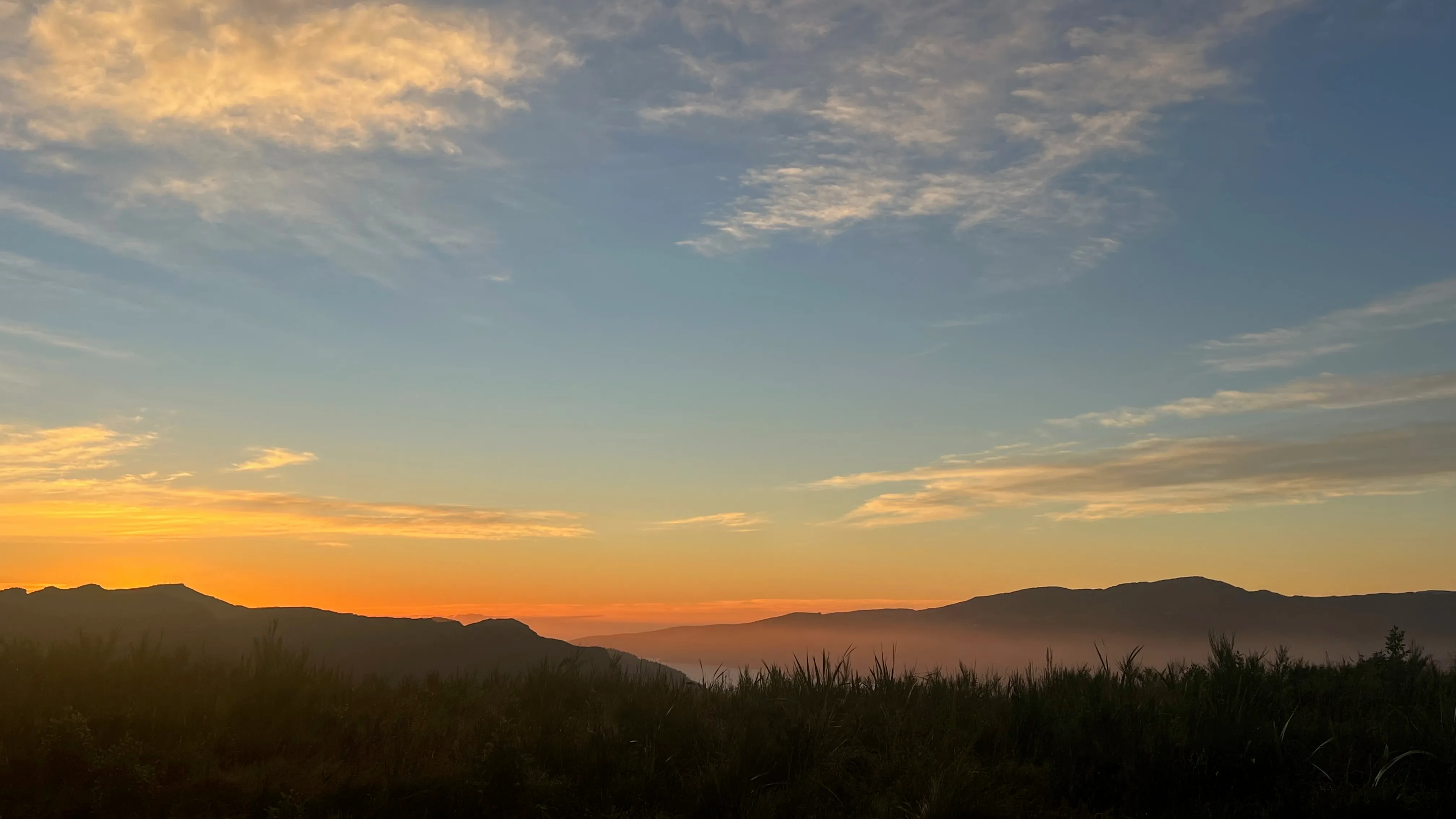 An orange dawn glow behind silhouetted hills.