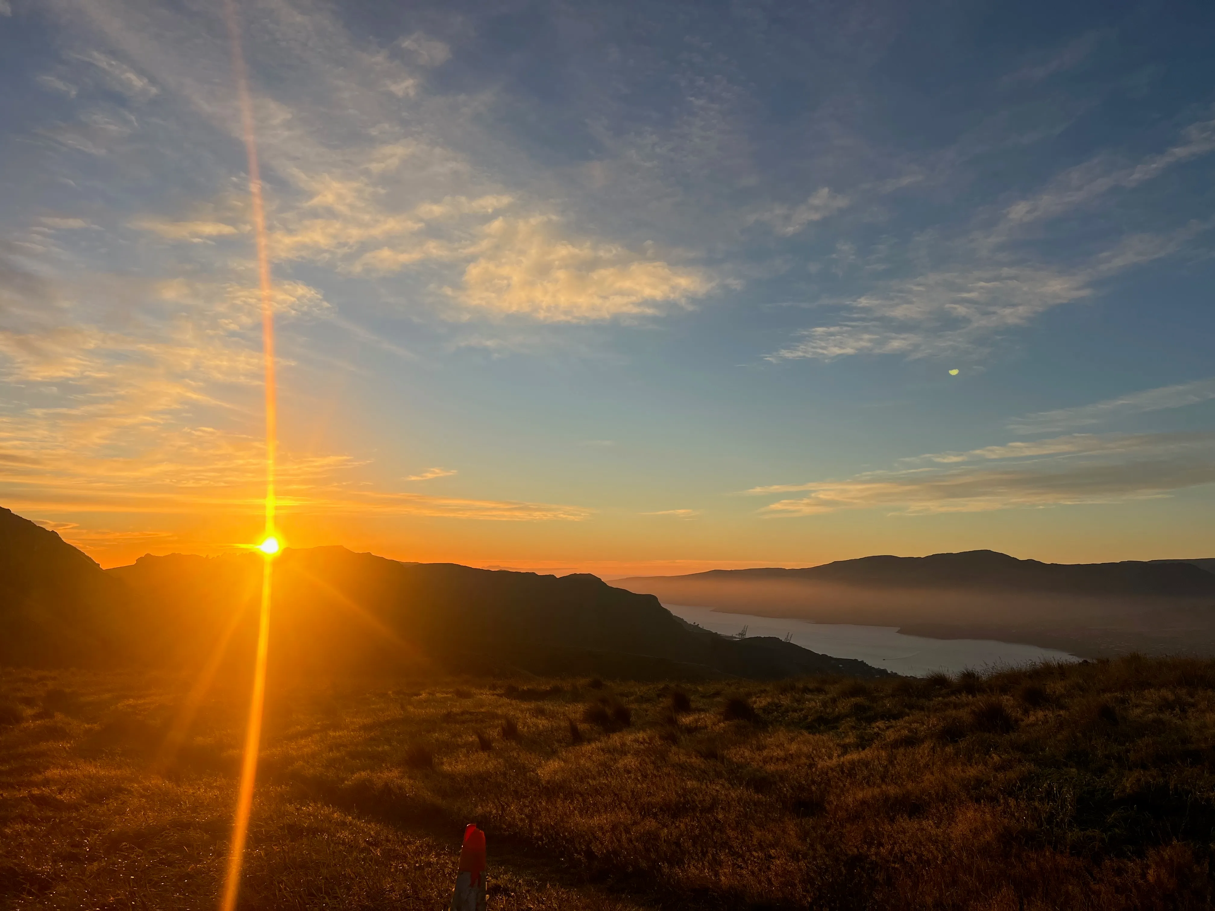 The sun rising over the hills, with the harbour below.