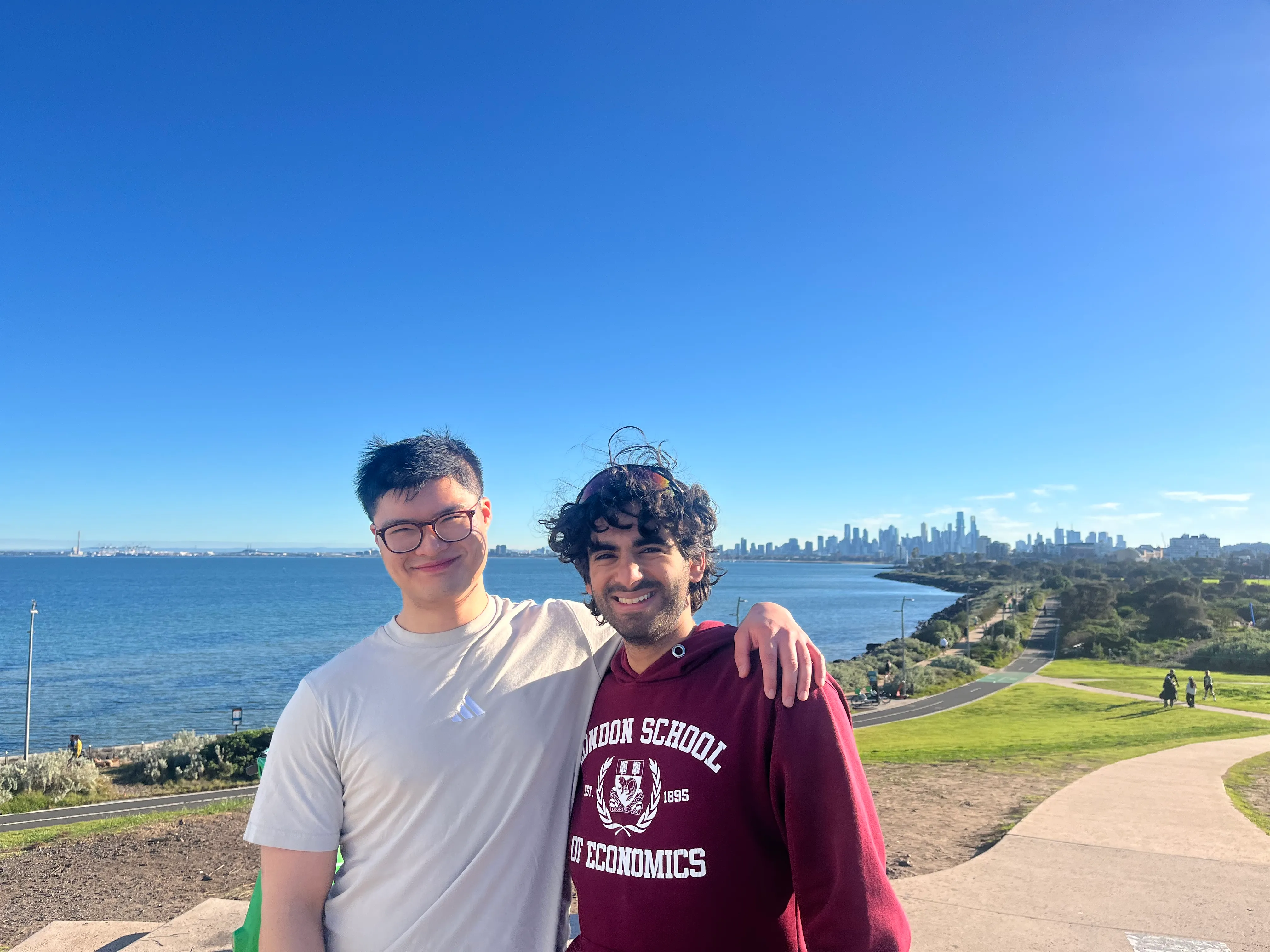 Two friends on the bayside path with the city skyline behind them.