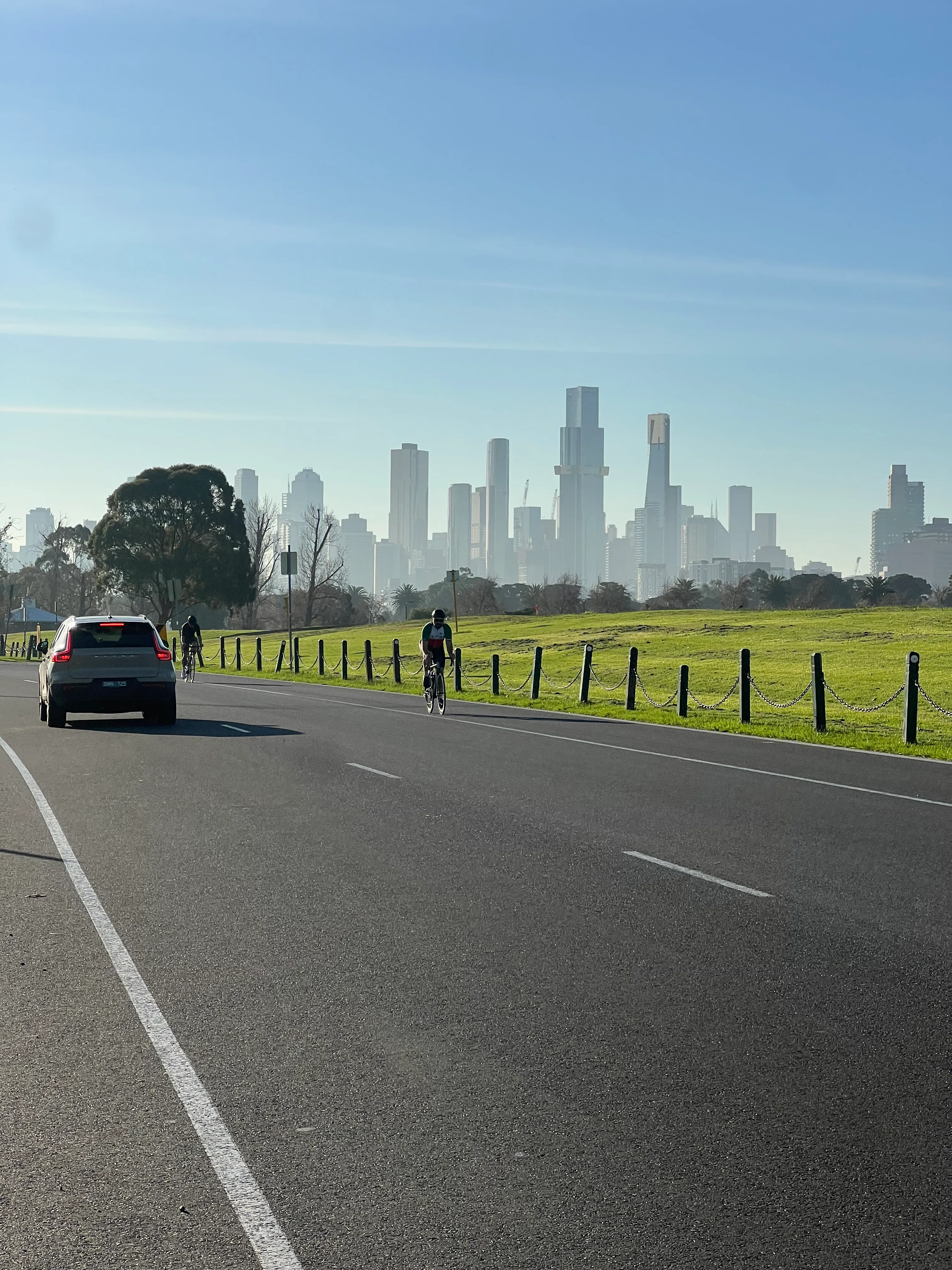 Cyclists riding along a road toward the city skyline.