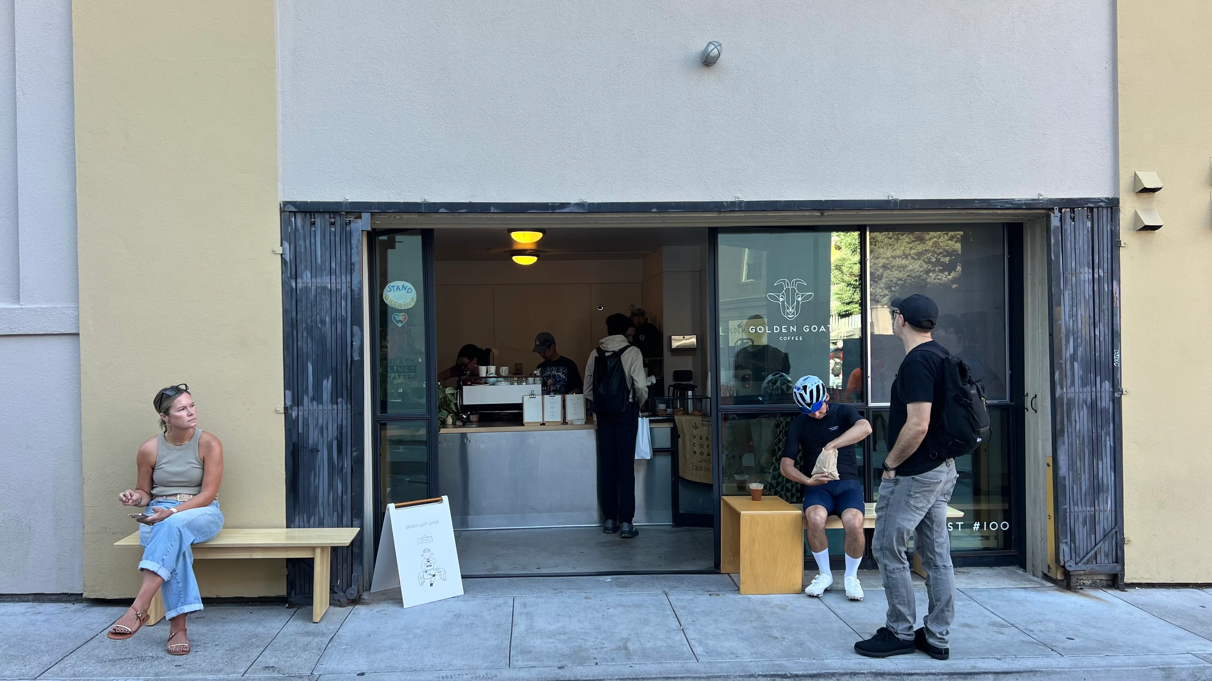 People outside a café storefront in the morning.
