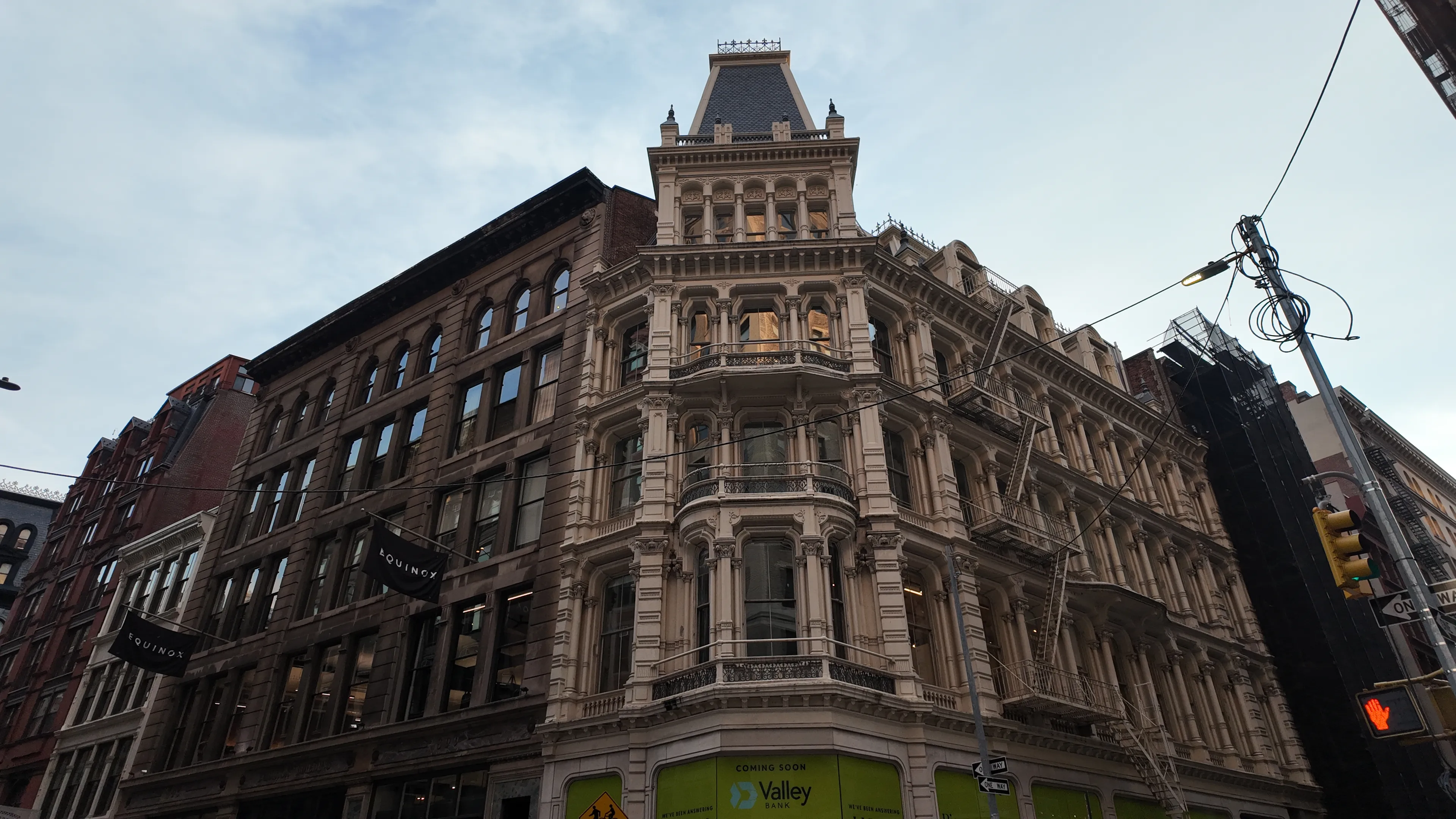 An ornate stone corner building beside brick apartment buildings.