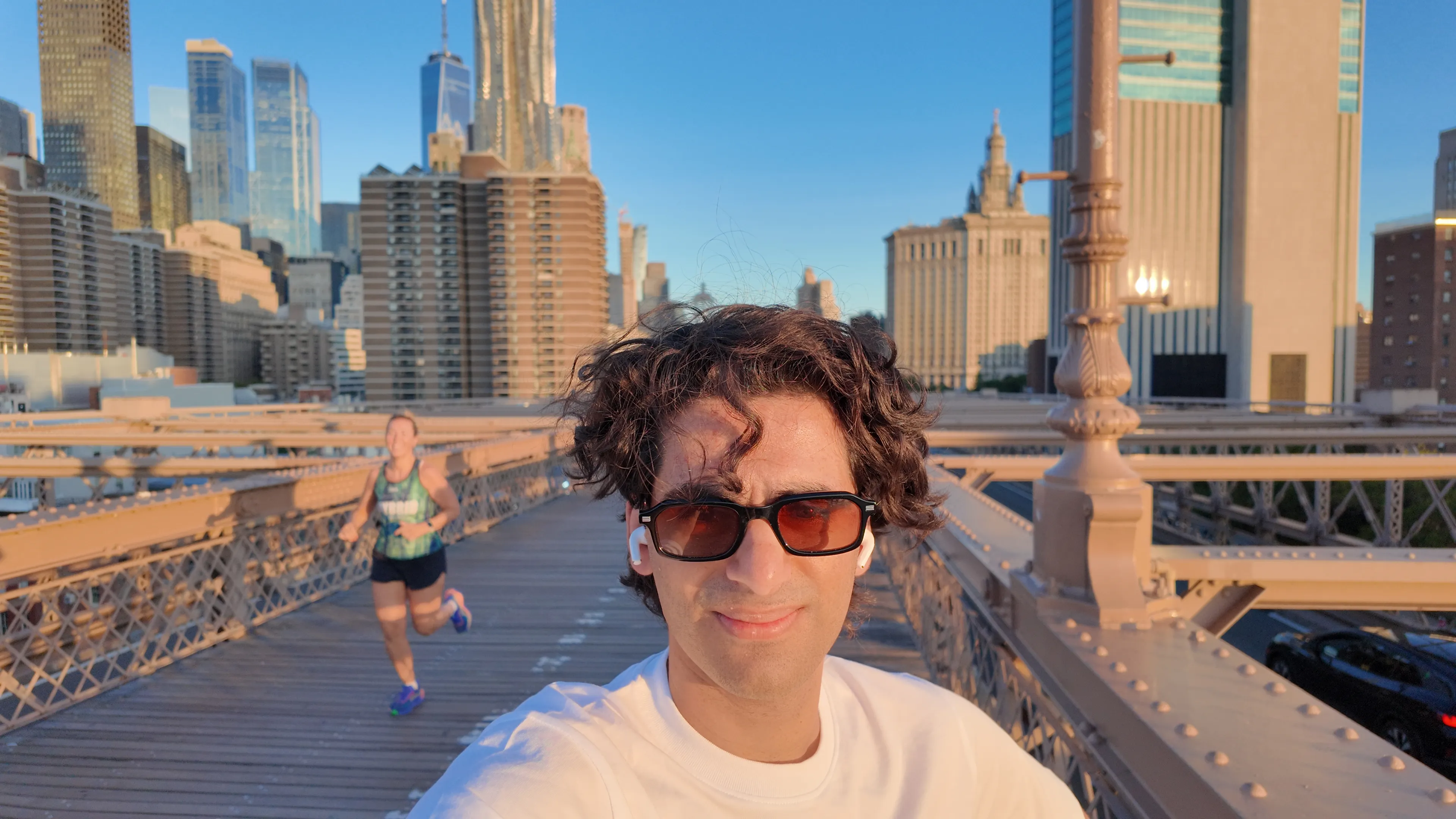 A person on a bridge walkway with the city skyline behind.