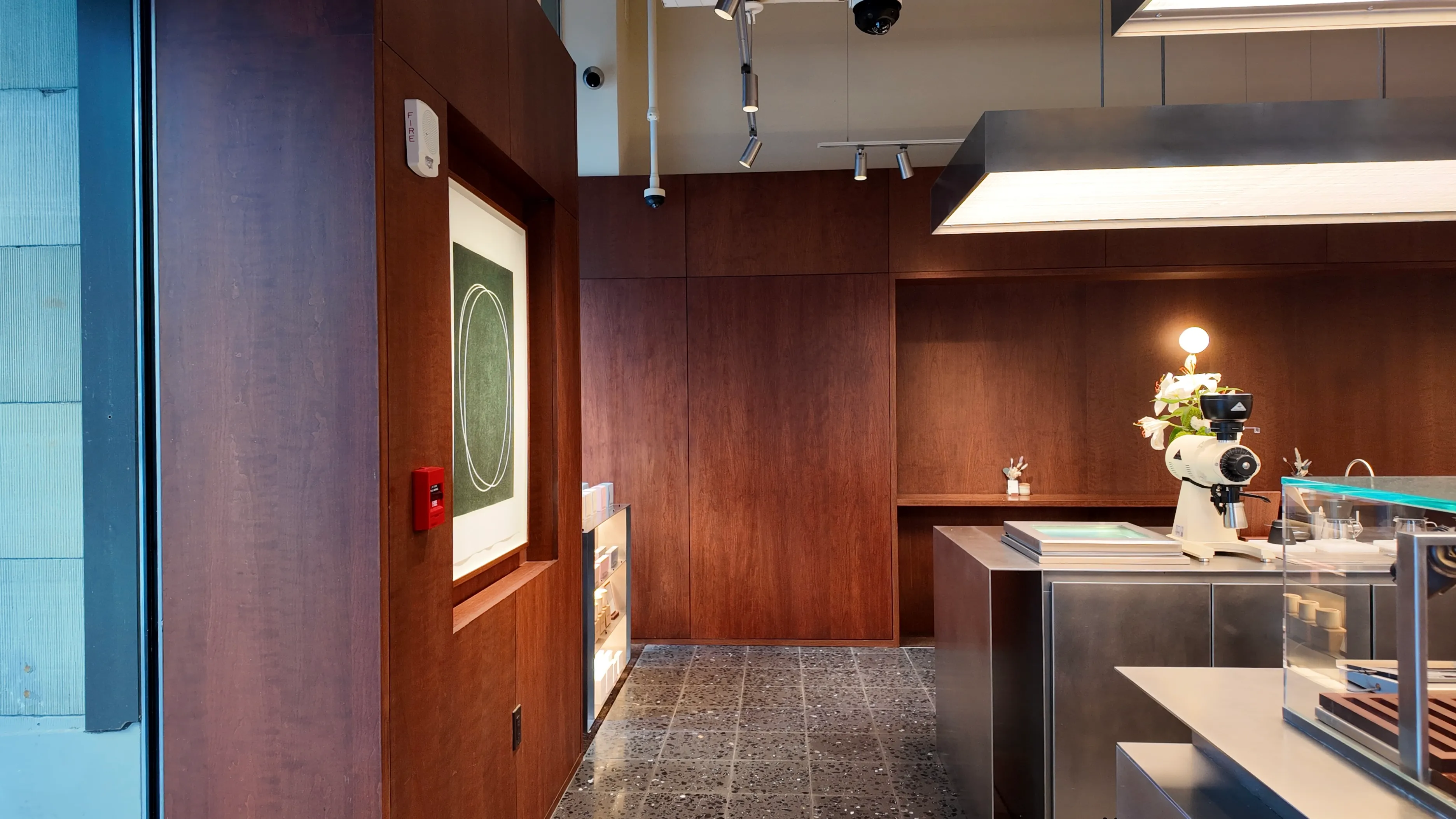A wood-panelled cafe counter with flowers and framed artwork.
