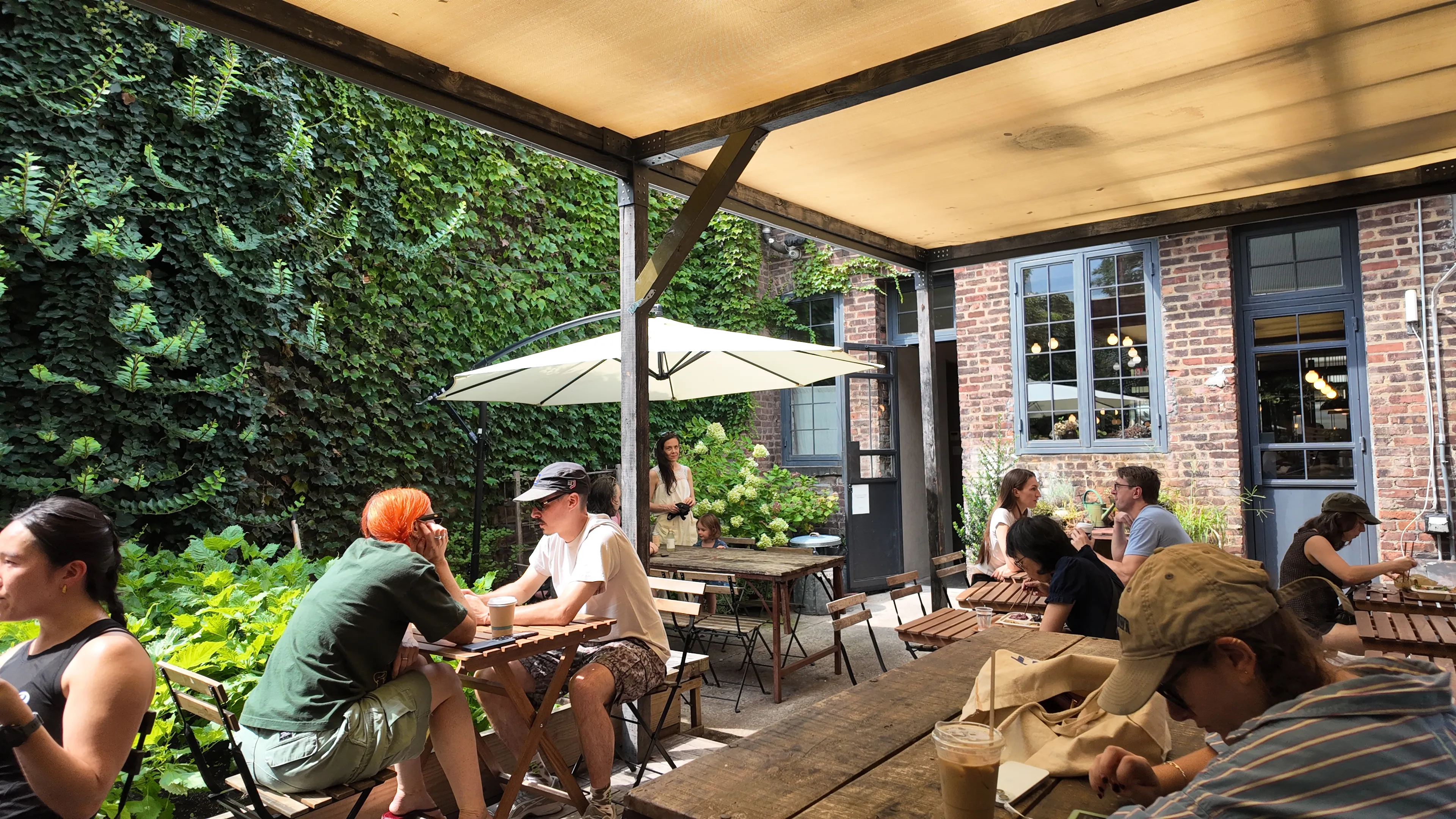 People seated in a leafy outdoor cafe courtyard.