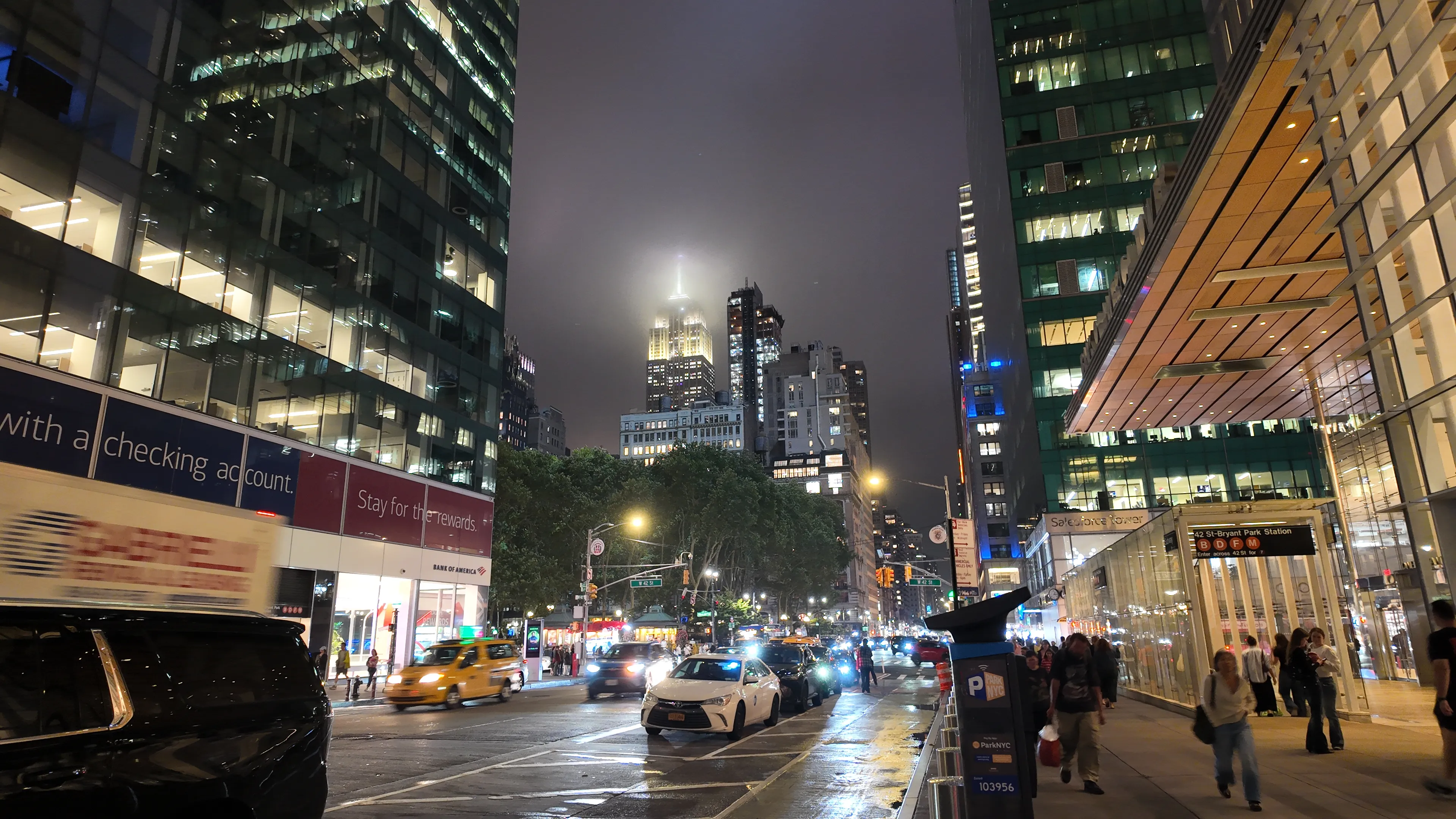 A busy city street at night beneath brightly lit office buildings.