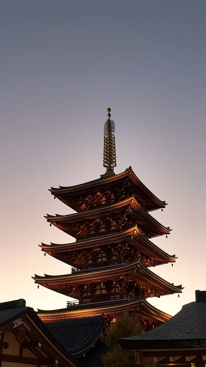 An illuminated multi-storey pagoda against a dusk sky.